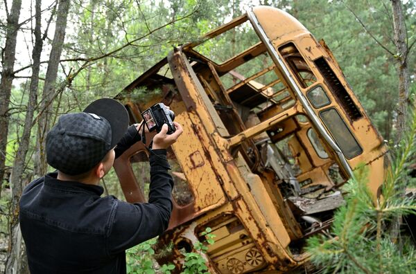 Турист фотографирует автобус в зоне отчуждения Чернобыльской АЭС - Sputnik Кыргызстан