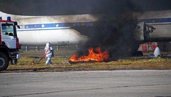 Сотрудник пожарной службы тушит горящий участок у самолета ИЛ-62 во время учений. Архивное фото - Sputnik Кыргызстан