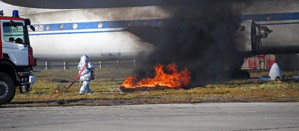 Сотрудник пожарной службы тушит горящий участок у самолета ИЛ-62 во время учений. Архивное фото - Sputnik Кыргызстан