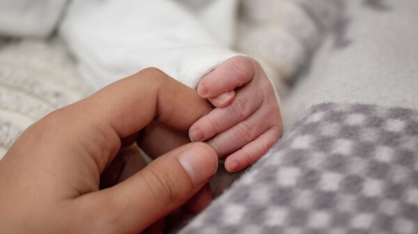 Женщина держит новорожденного ребенка за руки - Sputnik Кыргызстан