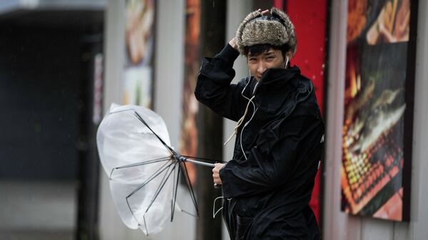 Горожанин держит сломанный зонт, во время сильного ветра. Архивное фото - Sputnik Кыргызстан