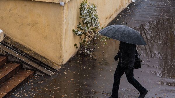 Мужчина с зонтом идет по улице в Бишкеке. Архивное фото - Sputnik Кыргызстан