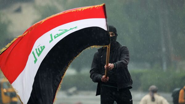 Иракский демонстрант с иракским флагом в ходе продолжающихся антиправительственных протестов в Багдаде. - Sputnik Кыргызстан