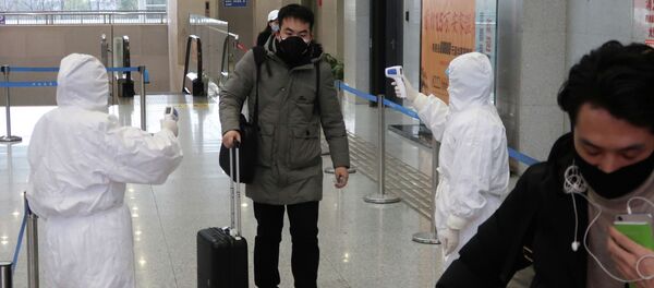 Рабочие в защитных костюмах проверяют температуру пассажира, прибывающего в город Сяньнин, граничащим с Уханом, Китай. 24 января 2020 года - Sputnik Кыргызстан