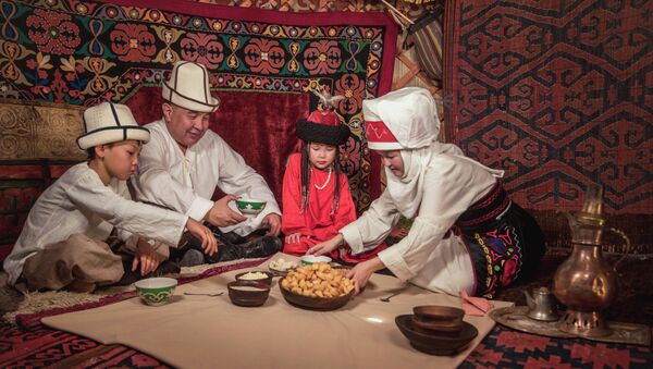 Семья в национальной одежде кыргызов сидят за дасторконом в юрте. Архивное фото - Sputnik Кыргызстан