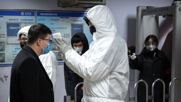 Медицинский работник в защитном костюме измеряет температуру пассажира у входа на станцию метро в Пекине. 26 января 2020 года - Sputnik Кыргызстан