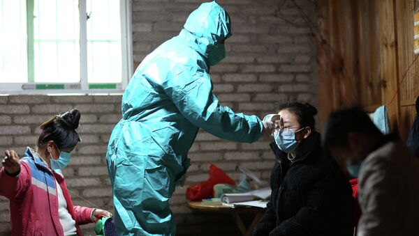 Медицинский работник в защитном костюме проверяет температуру девушки. Архивное фото - Sputnik Кыргызстан