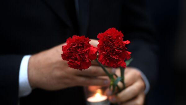Цветы и зажженная свеча в руках. Архивное фото - Sputnik Кыргызстан