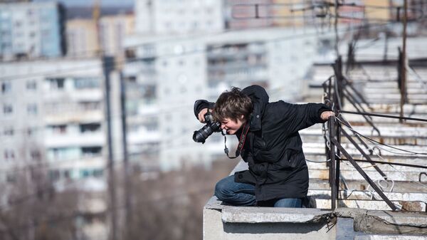 Мужчина фотографирует находясь на крыше дома. Архивное фото - Sputnik Кыргызстан