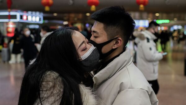 Пара в защитных масках целуется перед отъездом на железнодорожном вокзале Пекина. Архивное фото - Sputnik Кыргызстан