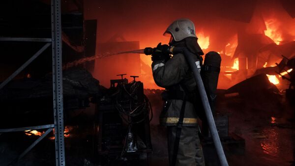 Сотрудник пожарной службы во время тушения пожара на складе. Архивное фото - Sputnik Кыргызстан