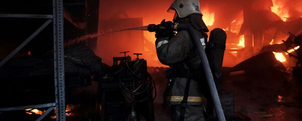 Сотрудник пожарной службы во время тушения пожара на складе. Архивное фото - Sputnik Кыргызстан