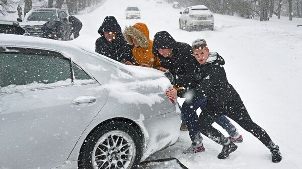 Люди толкают машину на одной из занесенных снегом улиц. Архивное фото - Sputnik Кыргызстан