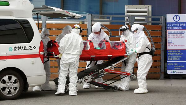 Медицинские работники в защитных костюмах доставляют зараженного коронавирусом в больницу, Чхунчхон, Южная Корея. 22 февраля 2020 года - Sputnik Кыргызстан