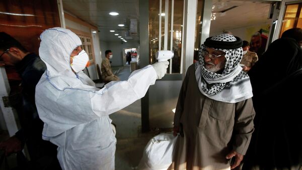 Иракский медицинский сотрудник проверяет температуру пассажира по прибытии на пограничный переход Шаламча между Ираком и Ираном, 20 февраля 2020 года - Sputnik Кыргызстан