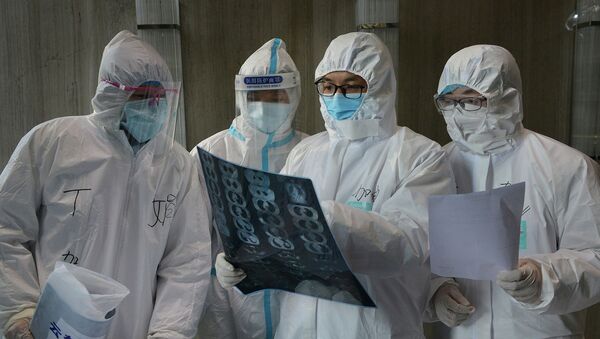 Медицинские работники в защитных костюмах осматривают снимок компьютерной томографии зараженного коронавирусом - Sputnik Кыргызстан