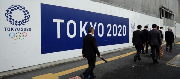 Пешеходы проходящие мимо логотипа летних олимпийских игр в Токио - Sputnik Кыргызстан