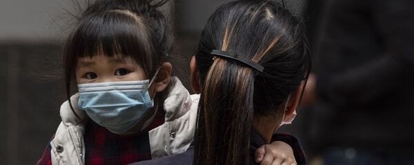 Девочка в защитной маске на руках у матери на одной из улиц в Гонконге. Архивное фото - Sputnik Кыргызстан