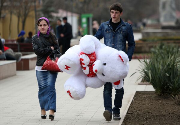 Мужчина несет подаренного девушке плюшевого медведя накануне праздника 8 марта в Грозном - Sputnik Кыргызстан
