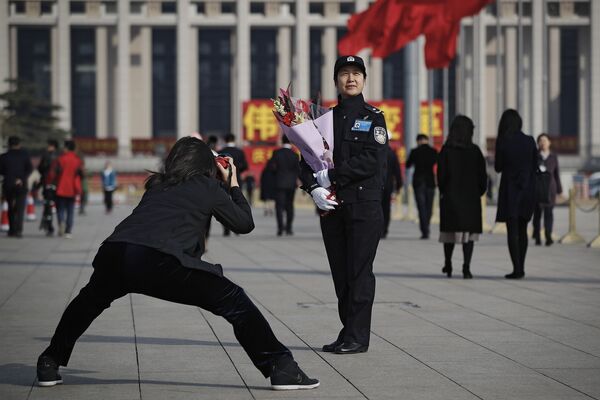 Женщина фотографирует женщину-полицейского 8 марта в Пекине - Sputnik Кыргызстан