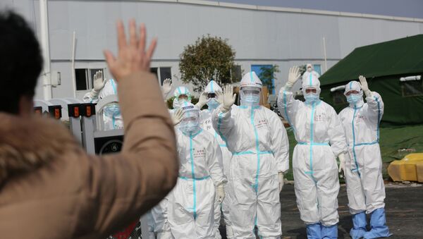 Медицинский персонал в защитных костюмах машут пациенту, который выписывается из больницы после выздоровления от коронавируса в провинции Ухань, Китай - Sputnik Кыргызстан