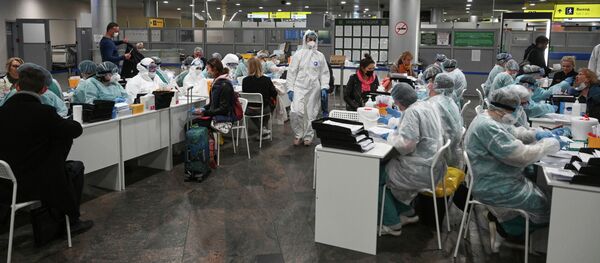 Медицинский персонал в защитном снаряжении проверяют пассажиров в качестве профилактической меры против коронавируса. Архивное фото Медицинский персонал в защитном снаряжении проверяют пассажиров в качестве профилактической меры против коронавируса. Архивное фото - Sputnik Кыргызстан