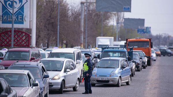Сотрудник патрульной милиции регулирует движение автомобилей на санитарно-карантинном посту на въезде в город Бишкек - Sputnik Кыргызстан