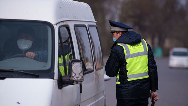 Сотрудник правоохранительных органов проверяют документы водителей на въезде в город Бишкек. Архивное фото - Sputnik Кыргызстан