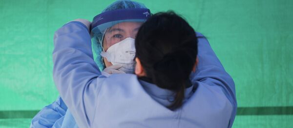 Медицинский работник одевает защитный костюм на площадке для тестирования коронавируса COVID-19 в Сиэтле, США. 26 марта 2020 года - Sputnik Кыргызстан