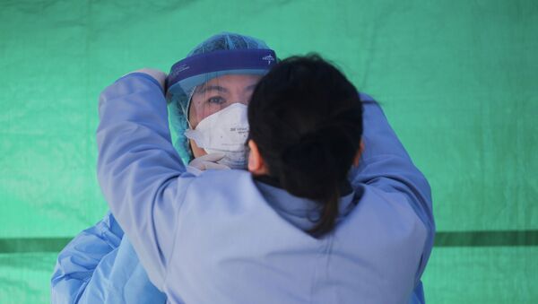 Медицинский работник одевает защитный костюм на площадке для тестирования коронавируса COVID-19 в Сиэтле, США. 26 марта 2020 года - Sputnik Кыргызстан