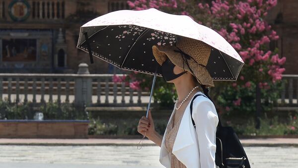 Люди в маске используют зонт для защиты от солнца. Архивное фото - Sputnik Кыргызстан