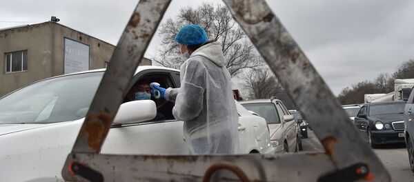 Медицинский персонал в защитном снаряжении проверяет температуру водителей и пассажиров на КПП. Архивное фото - Sputnik Кыргызстан