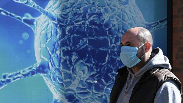 Мужчина в маске проходит мимо плаката где изображен коронавирус COVID-19 - Sputnik Кыргызстан