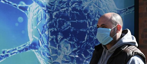 Мужчина в маске проходит мимо плаката где изображен коронавирус COVID-19 - Sputnik Кыргызстан