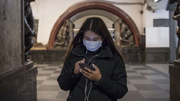 Девушка в медицинской маске смотрит в телефон. Архивное фото - Sputnik Кыргызстан