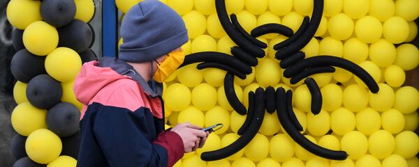 Молодой человек в защитной маске проходит мимо знака Опасность. Архивное фото Молодой человек в защитной маске проходит мимо знака Опасность. Архивное фото - Sputnik Кыргызстан