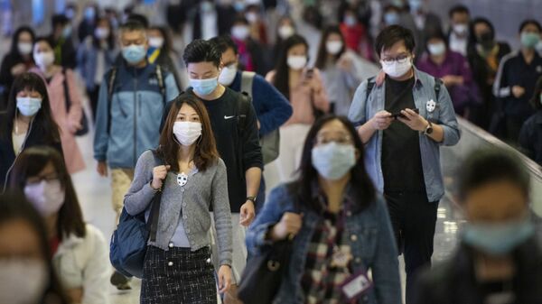 Люди в медицинских масках на переходе одной из станций метро в Гонконге. Архивное фото - Sputnik Кыргызстан