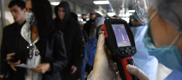 Медицинские сотрудники измеряют температуру пассажиров с помощью темпловизора. Архивное фото - Sputnik Кыргызстан
