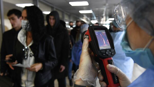 Медицинские сотрудники измеряют температуру пассажиров с помощью темпловизора. Архивное фото - Sputnik Кыргызстан