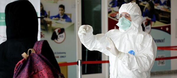 Медициналык кызматкер коопсуз костюмчан кишинин температурасын тепловизор менен текшерип жатат. Архив - Sputnik Кыргызстан