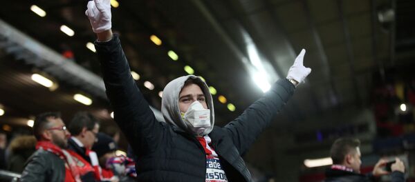 Фанат футбольной команды в защитной маске на стадионе перед матчем - Sputnik Кыргызстан