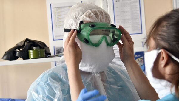 Врач городской больницы одевает защитный комбинезон, очки, маску, перчатки. Архивное фото - Sputnik Кыргызстан
