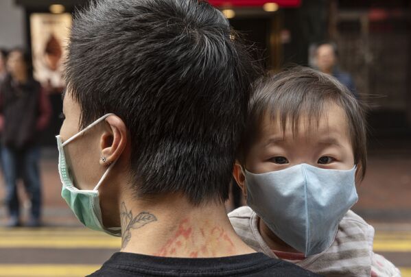 Ребенок в защитной маске на руках отца на одной из улиц в Гонконге - Sputnik Кыргызстан