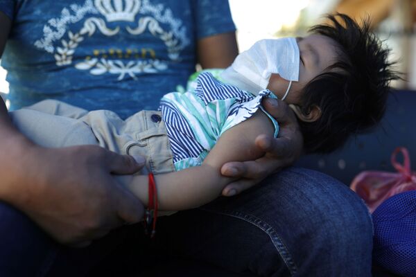 Мужчина со спящим ребенком в медицинской маске на руках в Сантьяго, Чили - Sputnik Кыргызстан