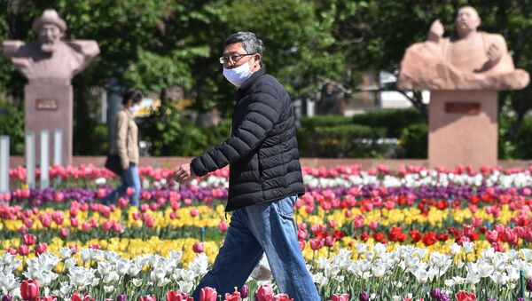 Мужчина в лицевой маске ходит среди цветущих тюльпанов в центре Бишкека - Sputnik Кыргызстан