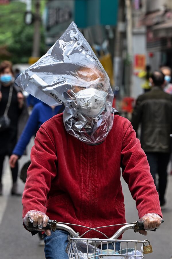 Велосипедист в защитной маске и с пластиковым пакетом на голове на одной из улиц Уханя, Китай - Sputnik Кыргызстан