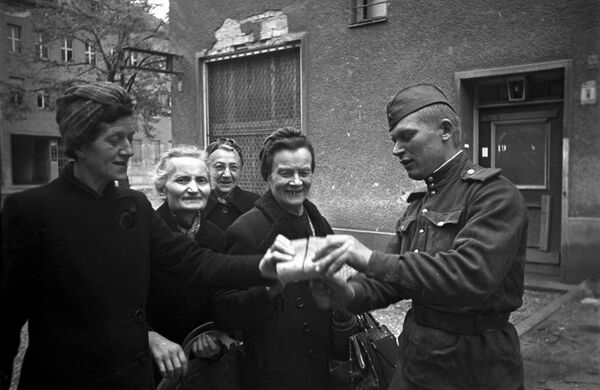 Советский солдат раздает хлеб женщинам Берлина, 7 мая 1945 года - Sputnik Кыргызстан