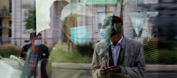 Человек в защитной маске, ожидающий на остановке, отражается в окне автобуса - Sputnik Кыргызстан