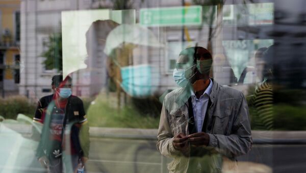 Человек в защитной маске, ожидающий на остановке, отражается в окне автобуса - Sputnik Кыргызстан