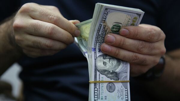 Мужчина пересчитывает купюры долларов США. Архивное фото - Sputnik Кыргызстан